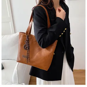 Détail d'un sac cabas marron en cuir avec pompon tissé décoratif et étiquette tendance