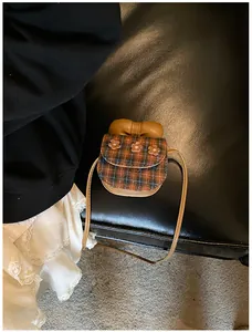 Detail of mini plaid crossbody bag featuring orange texture and 3D floral accents