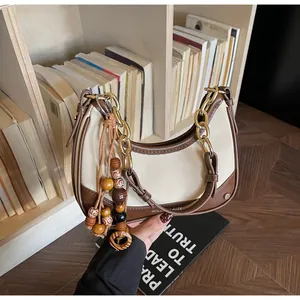 Detail of retro color-block crescent bag with gold chain and decorative wooden beads