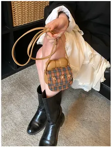 Detail view of mini plaid crossbody bag with leather bow and floral 3D accents