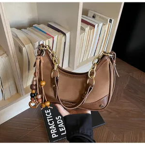Detail view of brown crossbody bag with chunky gold chain and wooden bead tassel decor