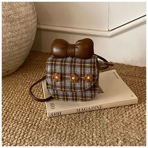 Close-up of checkered mini crossbody bag with a large leather bow and 3D floral accents