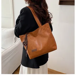 Détail d'un sac cabas vintage marron avec nœud tressé et étiquette mode sur le côté
