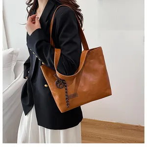 Détail du grand sac cabas marron en cuir texturé avec étiquette mode et bijou de sac
