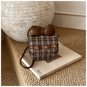 Close-up of vintage plaid mini bag with brown leather bow and embroidered flower details