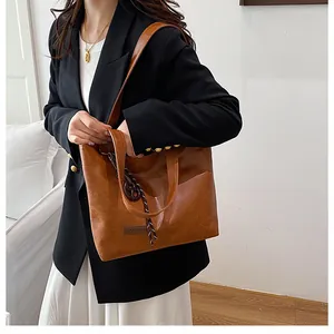Détail d'un sac cabas en cuir marron avec écusson FASHION et breloque tressée
