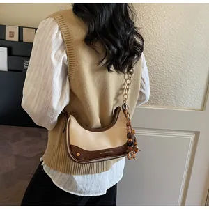 Detail of crossbody half-moon bag with color-block leather and wooden bead tassel