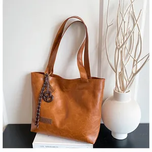 Détail du sac cabas marron caramel avec étiquette en cuir et pendentif décoratif