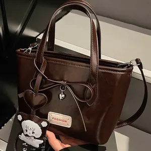 Glänzende schokobraune Tragetasche mit Lederschleife, Herzanhänger und Schaf-Anhänger
