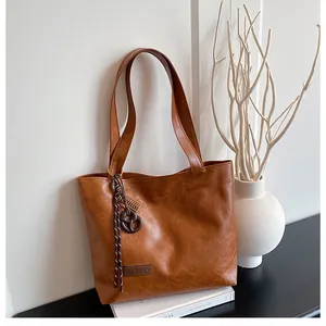 Détail du sac cabas en cuir marron avec logo Fashion et pendentif en corde torsadée