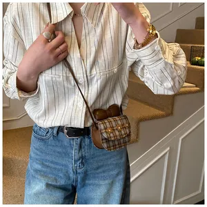 Detail of a mini plaid crossbody bag with a cute brown bow and small flower accents