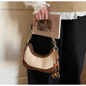 Close-up of contrast patchwork handbag with gold chain strap and wooden bead tassel