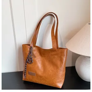 Détail d'un sac cabas marron avec un patch en cuir et une breloque en corde tressée