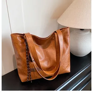 Détail du sac cabas vintage en cuir marron avec étiquette en cuir et corde tressée