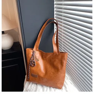 Détail d'un sac cabas marron montrant la texture cuir grainé et le charme en métal