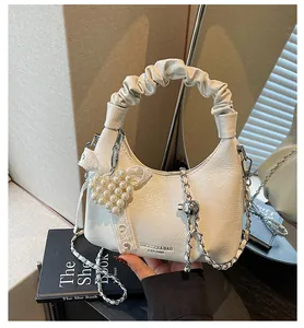 Detail of white ruched handbag with pearl heart charm and metallic chain strap