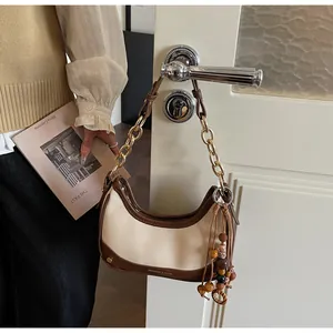 Detail of retro cream and brown contrast half-moon bag with chain strap and bead charm