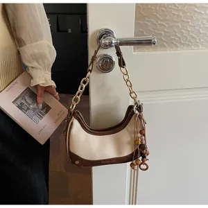 Close-up of contrast leather chain bag with beads hanging on a white door handle