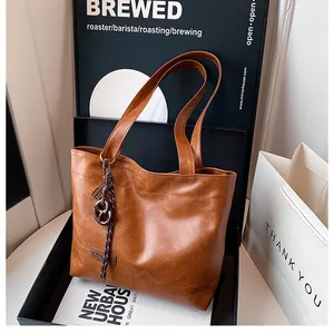 Détail d'un cabas marron caramel avec de fines bretelles et un pendentif en corde tressée