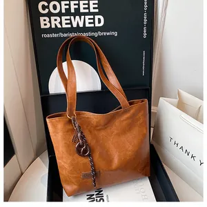 Gros plan sur le sac fourre-tout marron en similicuir montrant l'étiquette mode et les anses