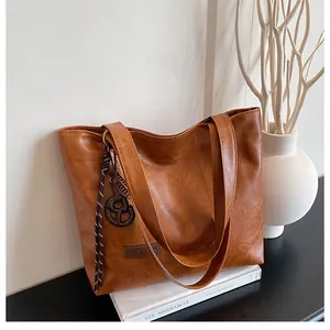 Détail d'un cabas en cuir PU marron avec étiquette Fashion et breloque tissée élégante