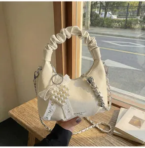 Detail of cream mini handbag with pleated handle, heart pearl charm and lace bow decor