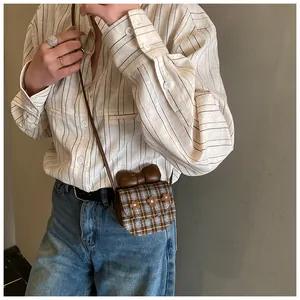 Detail of mini plaid crossbody bag with brown leather bow and floral accents