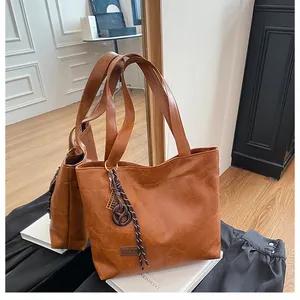 Détail d'un cabas en similicuir marron texturé avec breloque tissée et étiquette logo