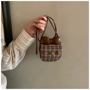 Detail of checkered crossbody coin purse with a large brown bow and floral accents