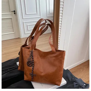 Gros plan sur la texture du sac cabas en cuir PU marron avec étiquette et pendentif