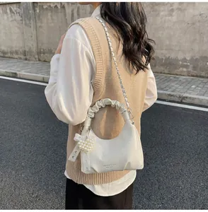 Detail of white pleated mini bag with metal chain strap and pearl heart charm