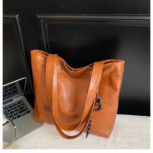 Détail d'un cabas marron en similicuir avec étiquette Fashion et pendentif à pompon