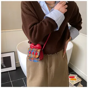 Mini red crossbody bag with plaid pattern, ribbon bow, and floral accents on a model