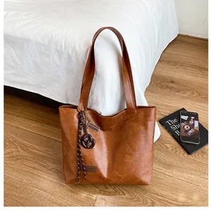 Détails du sac cabas en cuir marron vintage avec pendentifs et étiquette logo