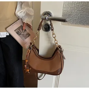 Detail of hobo bag featuring brown leather patchwork and gold chain strap in a lifestyle setting