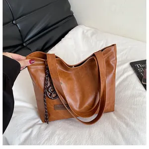 Vue détaillée d'un sac cabas marron avec texture litchi et pendentif circulaire
