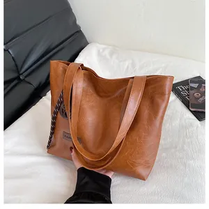 Détail du sac cabas en cuir marron avec corde tressée et étiquette de mode épurée