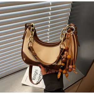 Detail of saddle bag featuring gold chain strap and decorative wood bead tassel