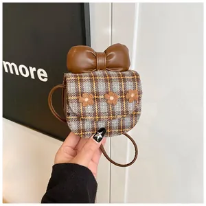 Detail of plaid mini crossbody bag featuring a large leather bow and floral felt accents