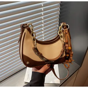 Close-up of crescent hobo bag with contrast stitching and wooden bead tassel detail