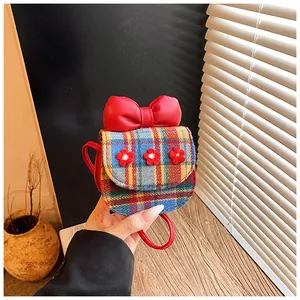 Close-up of cute plaid child's crossbody bag with red floral accents and large bow