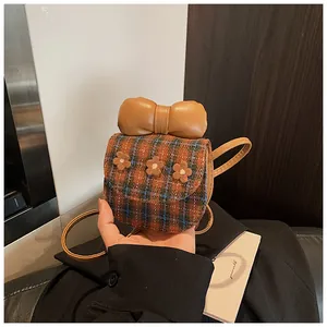 Detail shot of a mini checkered crossbody bag with 3D flowers and a large leather bow