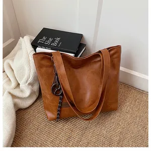 Détail d'un grand sac cabas marron texturé avec pendentif posé sur un tapis tressé