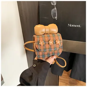 Macro detail of the mini plaid crossbody bag showing tweed texture and 3D floral accents
