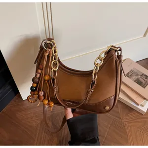 Close-up of brown patchwork crescent bag with gold chain and beaded tassel detail