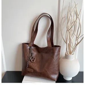 Détails du sac cabas en cuir marron foncé avec étiquette fashion et breloque en métal