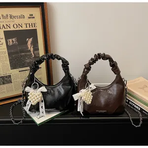 Close-up of pleated hobo bag with glossy crinkle leather and pearl heart charm accessory
