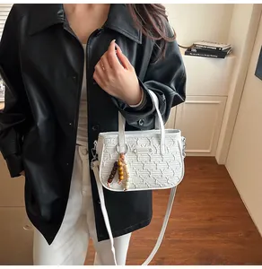 Détails de la texture matelassée blanche et du gland en perles de bois du sac