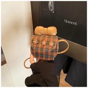 Detail of plaid tweed mini bag with leather bow, floral accents and slim shoulder strap