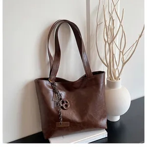 Détail du sac cabas en cuir marron foncé avec étiquette fashion et anneau métallique noué
